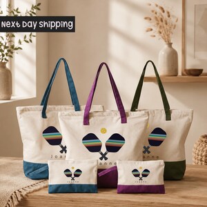A collection of colorful tote bags and small bags with tennis racket designs, arranged on a wooden surface.