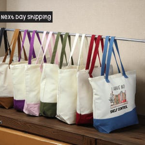 A row of colorful tote bags hanging on a rack, with a sign indicating next day shipping.