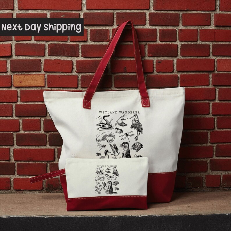 A large white tote bag with a red handle and a smaller white makeup bag with a red handle are displayed against a brick wall.
