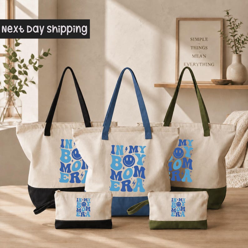 a collection of tote bags and a small bag, all with the same design and text printed on them. The text on the bags reads "IN MY BODY MOMERA".