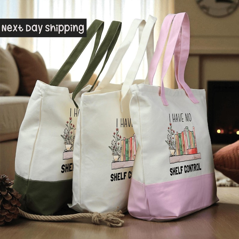 Three tote bags with the text "I HAVE NO SHELF CONTROL" printed on them, placed on a wooden surface.
