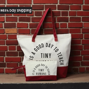 A large white tote bag with a red strap and a smaller red and white bag with a matching red strap are displayed against a brick wall, with a sign indicating "next day shipping".