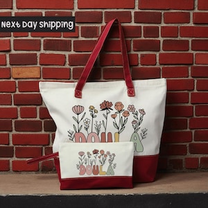 A large white tote bag with a red handle and a smaller matching bag are displayed against a brick wall, with a sign indicating next-day shipping.