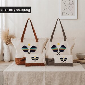 two tote bags with tennis racket designs, placed on a table with a vase and some books in the background.