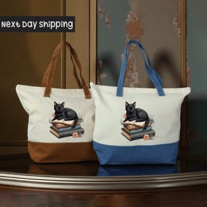 Two tote bags with a cat image on them, one white and one blue, placed on a wooden surface.