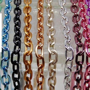 May include: A collection of colorful metal chain links in various shades, including blue, green, black, gold, silver, and pink. The text "OUT of GREEN" is vertically displayed in white.