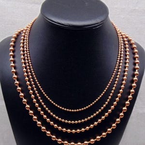 Each necklace is 24" long.  They are staggered on display to show the detail. Otherwise all four would hang at same length.