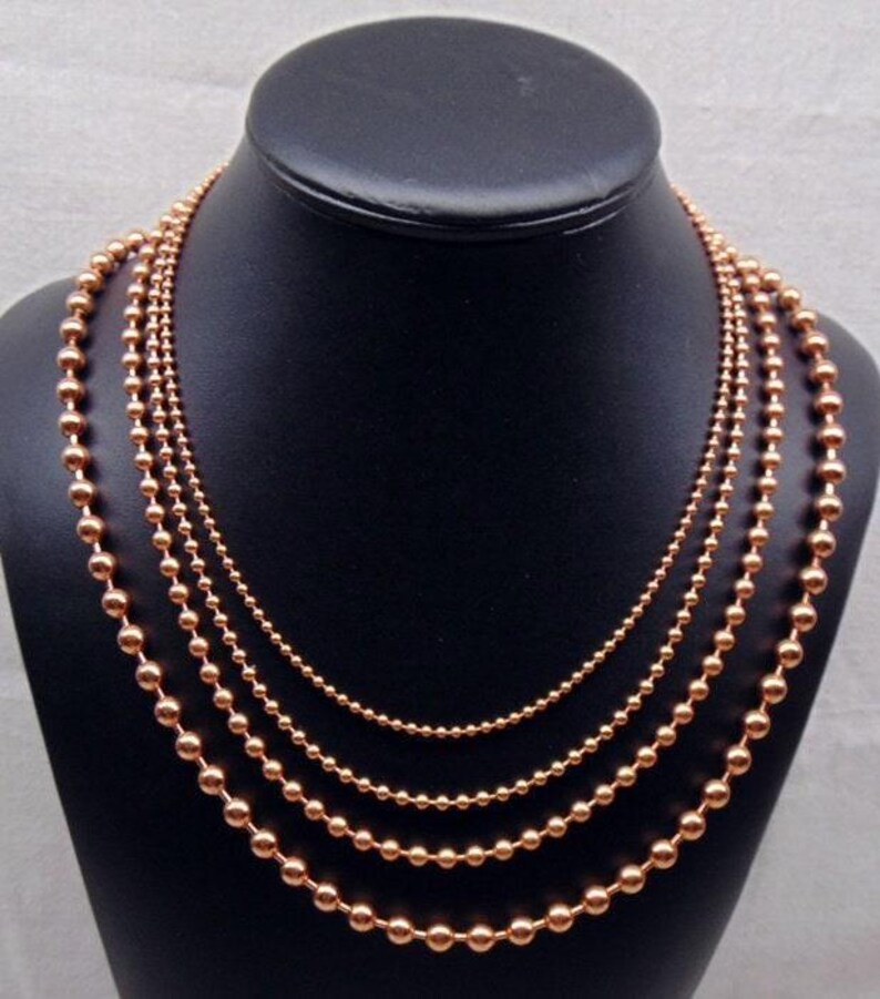 Each necklace is 24" long.  They are staggered on display to show the detail. Otherwise all four would hang at same length.