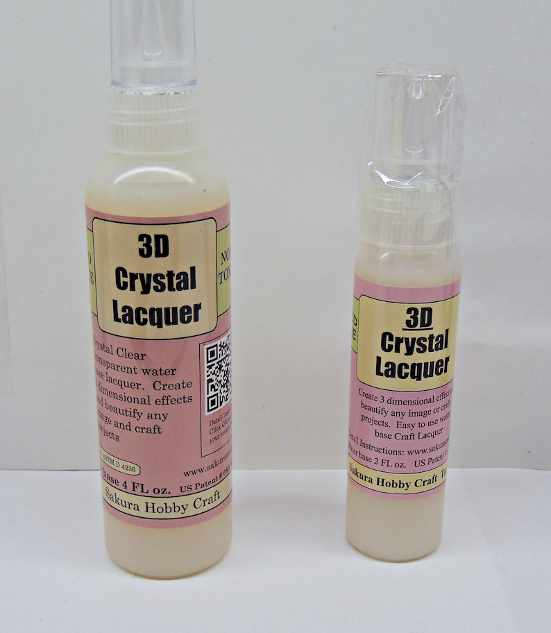 May include: Two bottles of 3D Crystal Lacquer. The bottles have a clear plastic cap and a pink and cream label with the product name and details. The larger bottle contains 4 fl oz of lacquer, and the smaller bottle contains 2 fl oz.