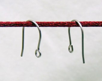 May include: Two silver-toned metal earring hooks with a curved shepherd's hook design and a small circular loop at the bottom for attaching jewelry components, suspended from a horizontal dark red textured cord.