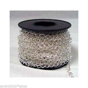 May include: A spool of silver-colored chain. The chain is made of small, oval-shaped links and is wound around a black plastic spool. The chain is likely used for jewelry making or other craft projects.