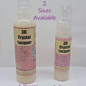 May include: Two bottles of 3D Crystal Lacquer, one 4 ounces and the other 2 ounces. The bottles have a clear spray nozzle and a pink and cream label. The text on the label says "3D Crystal Lacquer" and "Sakura Hobby Craft".