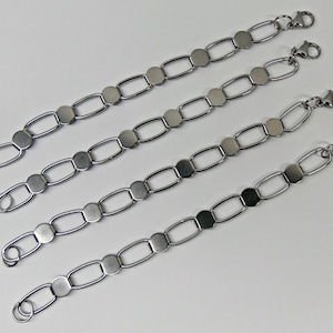 May include: Four silver-toned bracelets with a chain link design. Each bracelet features a series of oval links connected by circular links and a flat, circular accent. The bracelets have a lobster clasp closure.