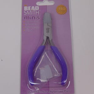 May include: The Bead Smith Minis mini chain nose nylon jaw pliers feature a polished steel head and purple PVC handles. The tool is packaged on a purple card with the text Bead Smith Minis, Pro Quality, and Mini Chain Nose Nylon Jaw Plier.
