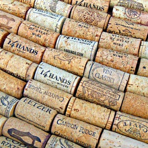 May include: A collection of used wine corks, featuring various winery names and logos. The corks are made of natural cork material and display a range of colors from light tan to brown. The text on the corks includes "14 Hands", "Fetzer", and "Canyon Ridge".