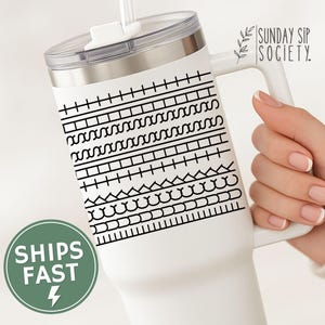 May include: White insulated tumbler with a handle and a lid. The tumbler features a black geometric pattern around the body. The text "SUNDAY SIP SOCIETY" is printed on the side.