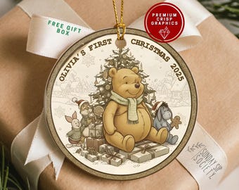 May include: A round Christmas ornament featuring Winnie the Pooh and friends in front of a Christmas tree. The ornament has the text "Olivia's First Christmas 2025". The ornament is gold-toned with a ribbon.