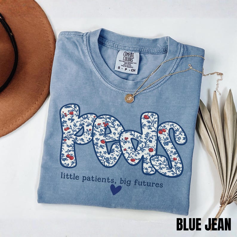 blue Jean Comfort Colors pediatric nurse shirt with floral “Peds” typography and quote “little patients, big futures,” trendy coquette style RN gift tee.