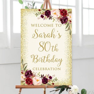 May include: Welcome to Sarah's 80th Birthday Celebration sign with gold glitter background and burgundy floral design.