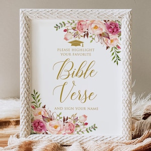 May include: White framed sign with floral accents and the text "PLEASE HIGHLIGHT YOUR FAVORITE Bible Verse AND SIGN YOUR NAME" in gold script. The frame has a textured, distressed finish, and the flowers are pink and purple.