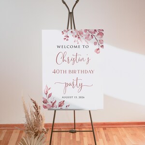 May include: Welcome to Christina's 40th Birthday party, 15 August 2026. A white sign with pink floral watercolour design and calligraphy text.