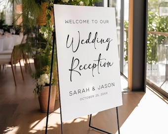 May include: White wedding reception sign with black text. The sign reads "Welcome to our Wedding Reception Sarah & Jason October 25, 20XX". The sign is on a black easel.
