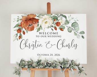 May include: Welcome sign with a floral design in shades of orange, white, and green. The sign reads "Welcome to our wedding, Christin & Charles, October 24, 2026".