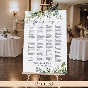 May include: A white seating chart with the words "find your seat" in elegant script, adorned with green foliage. The chart lists names alphabetically, with the names Sophia & Daniel and the date October 20, 20XX at the bottom. The word "Printed" is at the bottom.