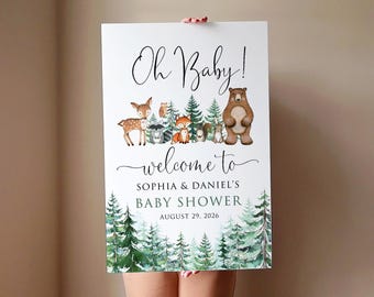 May include: A white sign with a woodland theme announcing a baby shower. The sign says "Oh Baby! Welcome to Sophia & Daniel's Baby Shower August 29, 2026". The sign features a watercolor illustration of a bear, deer, fox, and other woodland creatures.
