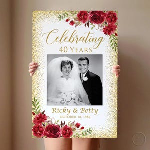 May include: A framed print celebrating a 40th wedding anniversary, with a black and white photo of a couple. The print has gold glitter and burgundy floral decorations. Text reads "Celebrating 40 Years" and "Ricky & Betty, October 18, 1986."