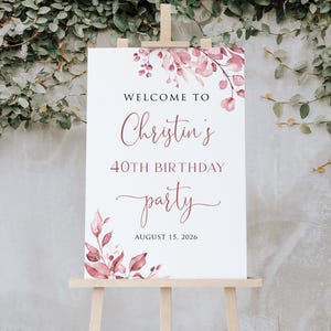 May include: Welcome to Christin's 40th Birthday party, 15 August 2026. A white sign with pink floral watercolour design.