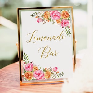 May include: A gold-framed sign with the words "Lemonade Bar" in elegant gold script. The sign is decorated with watercolor floral arrangements in shades of pink, orange, and green, perfect for a wedding or party.