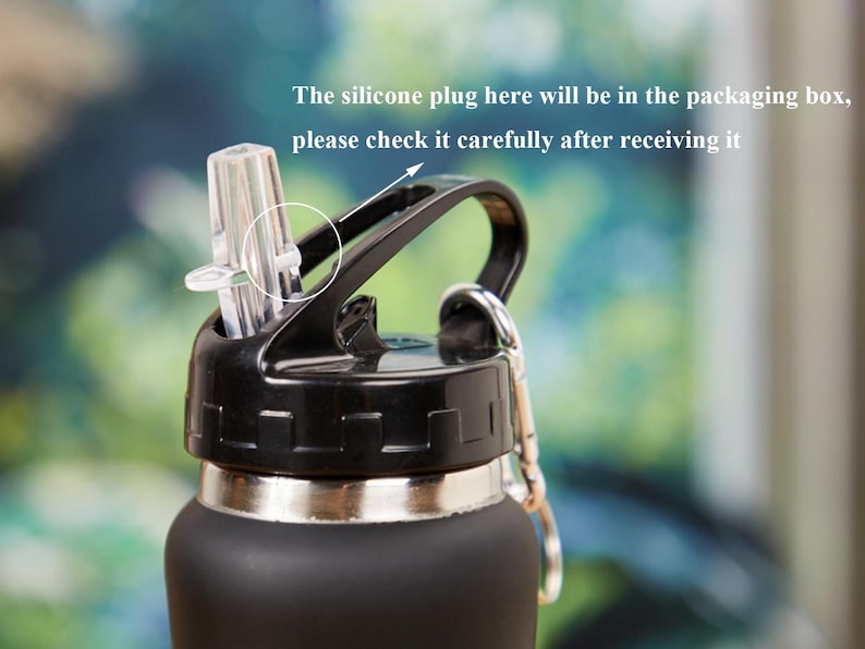 May include: Close-up of a black water bottle with a black lid and a clear straw. The lid has a handle and a silver ring for attaching a carabiner. Text on the image reads: "The silicone plug here will be in the packaging box, please check it carefully after receiving it."