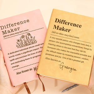 May include: Two notebooks with the text "Difference Maker" on the cover. One is pink, the other is tan. The pink notebook has a floral design and the name "Hi" at the bottom. The tan notebook has the name "Georgia" at the bottom.