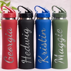 May include: Four personalized water bottles in red, black, blue, and green. Each bottle has a silver name: Georgia, Hedwig, Kristin, and Maggie. The bottles have a flip-top lid and a stainless steel base.