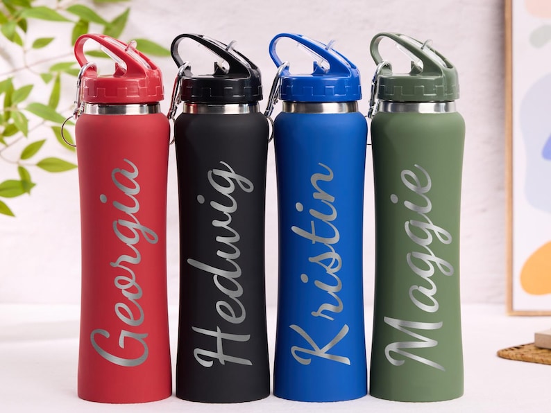 May include: Four personalized water bottles in red, black, blue, and green. Each bottle has a silver name: Georgia, Hedwig, Kristin, and Maggie. The bottles have a flip-top lid and a stainless steel base.