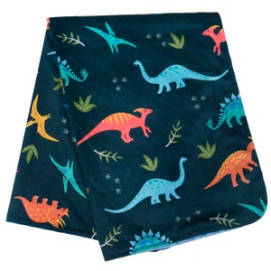 May include: A dark blue fleece blanket with a repeating pattern of colorful dinosaurs and green leaves.