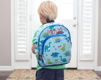 May include: A blue and green dinosaur-themed backpack with a white trim and a blue zipper. The backpack has a name tag that says "Michael".