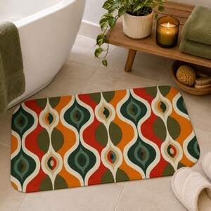 May include: A rectangular bath mat featuring a repeating mid-century inspired pattern of interconnected teardrop and wave shapes in vibrant shades of burnt orange, forest green, cream, and deep red, with rounded corners and a soft, flat-weave texture.