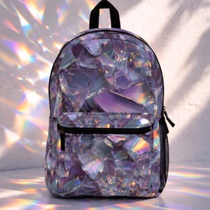 May include: A backpack with a unique, iridescent design. The bag features a pattern of purple and iridescent shapes, creating a shimmering effect. It has a black handle, a front pocket with a zipper, and a mesh side pocket. The overall design is eye-catching and stylish.