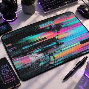 May include: A rectangular black mousepad with a vibrant, abstract design of colorful horizontal lines in shades of pink, blue, green, and yellow. The mousepad has a black border and is surrounded by computer accessories.