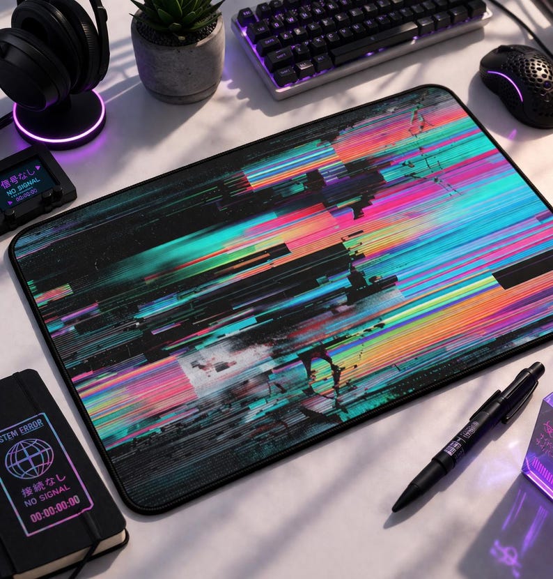 May include: A rectangular black mousepad with a vibrant, abstract design of colorful horizontal lines in shades of pink, blue, green, and yellow. The mousepad has a black border and is surrounded by computer accessories.
