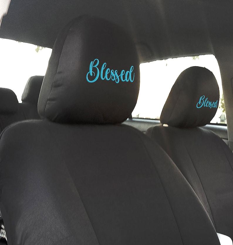 Puede incluir: Dos reposacabezas de asiento de coche negros con la palabra "Blessed" bordada en azul turquesa.