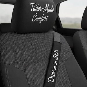 Puede incluir: Reposacabezas negro de asiento de coche con el texto bordado "Tailor-Made Comfort". También es visible una funda negra para el cinturón de seguridad con el texto "Drive in Style". El asiento del coche es negro con un patrón texturizado.