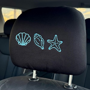 May include: A white ceramic mug with a black handle and the text "But First, Coffee" in a bold, black font. The mug is set against a blurred background, suggesting a cozy setting.