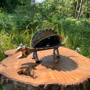 May include: A metal sculpture of a hedgehog made from recycled materials, including saw blades and a wrench. The sculpture is sitting on a wooden stump.