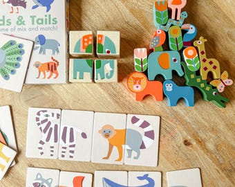 May include: A children's wooden matching game featuring animal illustrations. The set includes wooden blocks, matching cards, and a box labelled "Heads & Tails". The wooden animal figures include a lion, elephant, giraffe, and monkey.