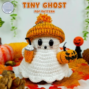 May include: A crocheted ghost wearing an orange and yellow hat and holding a small crocheted pumpkin. The ghost is white and has black eyes. The background is an autumnal scene with leaves and pumpkins.