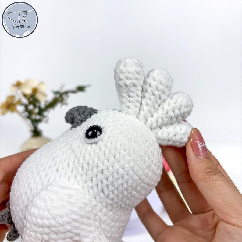 May include: White crocheted stuffed cockatoo with a gray beak and black eyes. The cockatoo has a large white crest on its head.