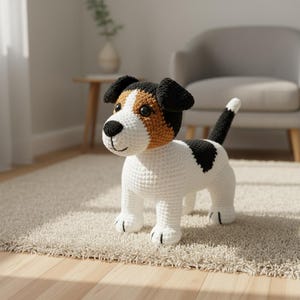 以下が含まれることがあります： 白、黒、タン色の犬の編みぐるみのおもちゃ。犬は黒い耳、背中の黒い斑点、白と黒の尻尾を持っています。おもちゃはベージュのラグの上に立っています。